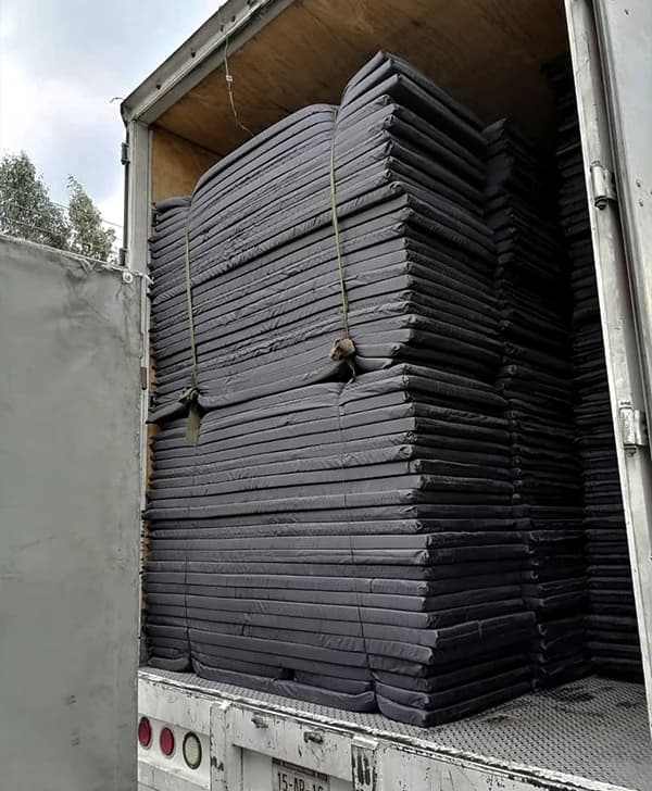 Colchones FSE apilados listos para entrega en un albergue